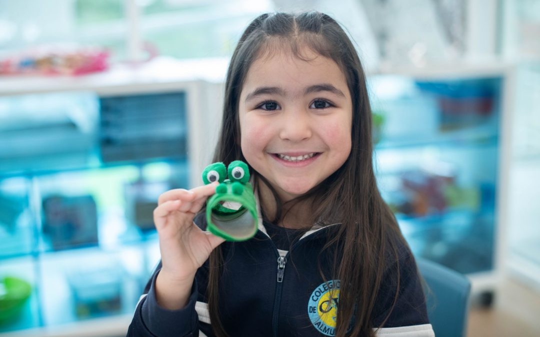 Una alumna con uniforme muestra a cámara una manualidad